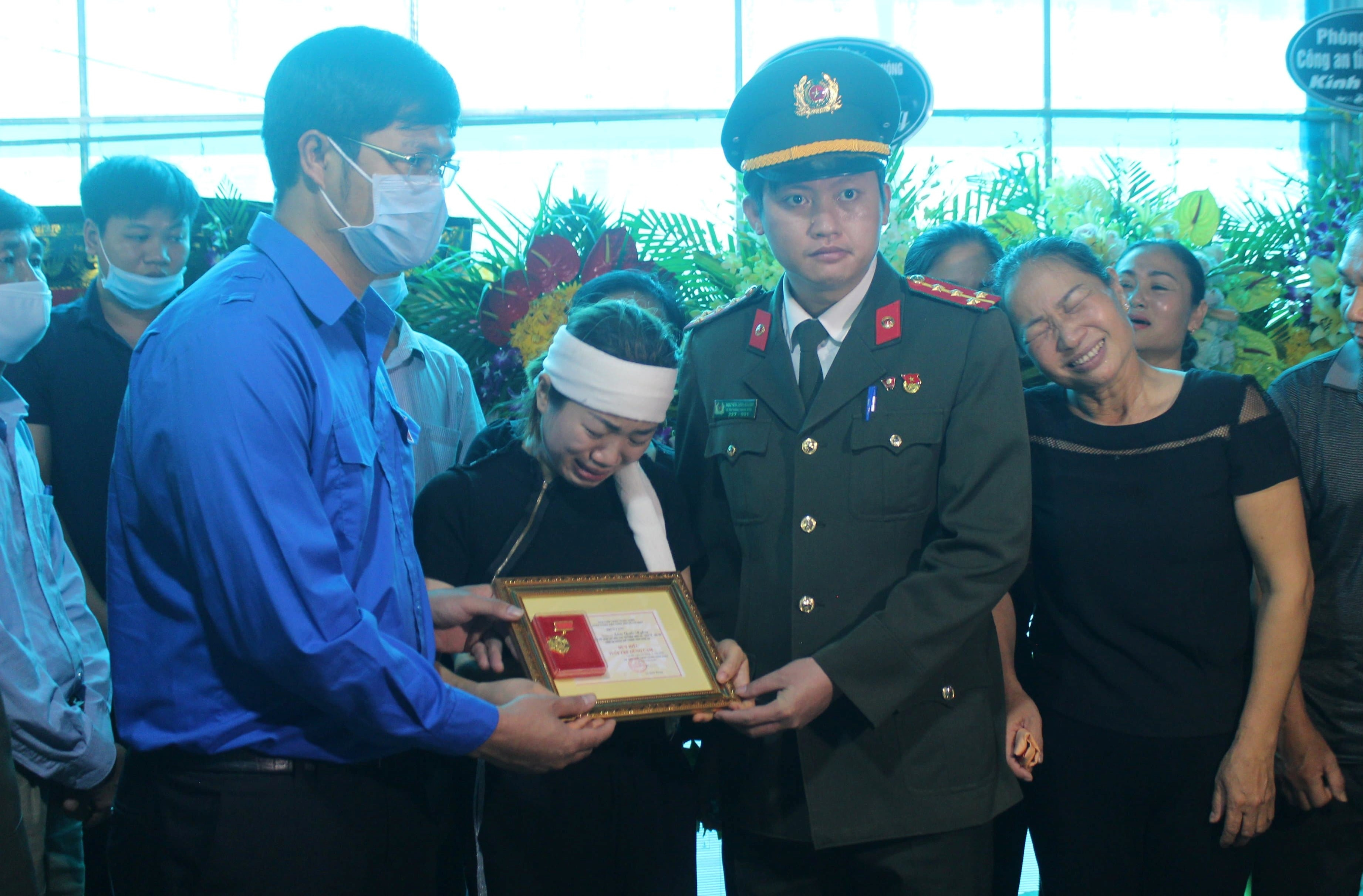 Vợ Thượng úy Nghĩa khóc lịm khi nhận Huy hiệu tuổi trẻ dũng cảm của chồng. Ảnh: CTV