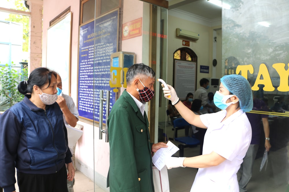 Kiểm tra thân nhiệt công dân trước khi vào Phòng chờ. Ảnh: Nguyễn Hải