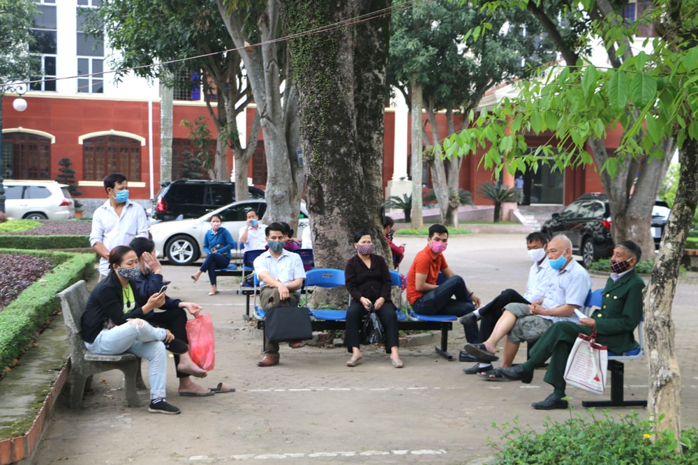 Người dân đến giao dịch được chia thành 2 nhóm ngồi tại khuôn viên sân UBND thành phố Vinh để chờ được gọi vào. Ảnh: Nguyễn Hải