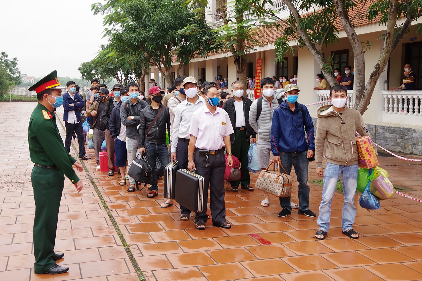 Mọi người xếp hàng ngay ngắn chờ đến lượt mình được đo thân nhiệt, kiểm tra sức khỏe trước khi ròi khỏi khu cách ly