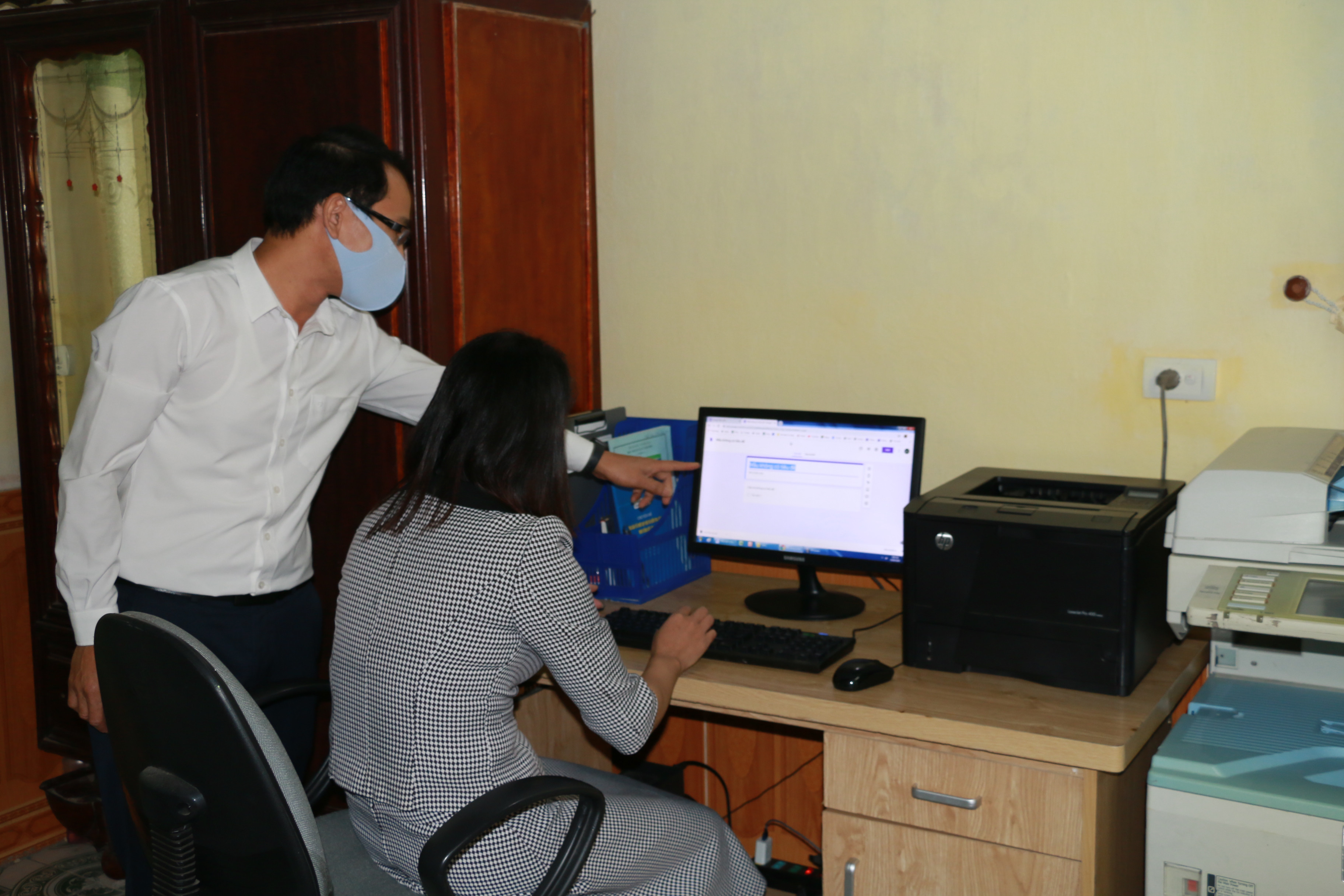 Thầy giáo Trần Văn Chung cùng đồng nghiệp đang kiểm tra lại việc thực hiện Phiếu bài tập Online ở nhà trường. Ảnh: Mỹ Hà