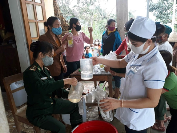 Thiếu tá Nguyễn Thị TRần Thanh hướng dẫn nhân dân trên địa bàn pha chế dung dịch nước sát khuẩn. Ảnh:Hải Thượng
