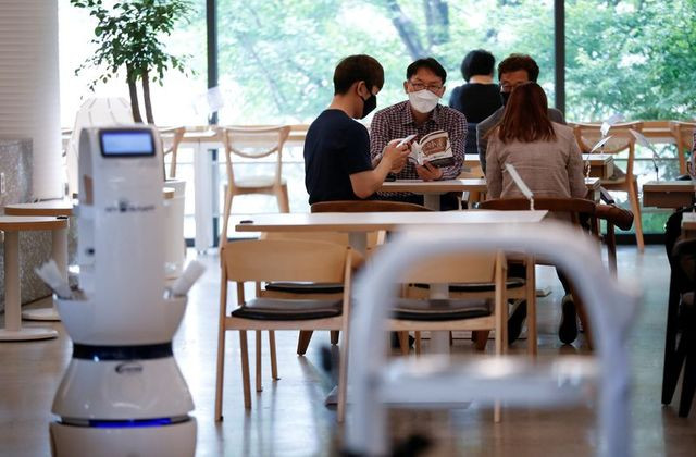 Khách hàng chờ robot nhận đơn, pha cà phê và phục vụ tận bàn tại Daejeon, Hàn Quốc. Ảnh: Reuters