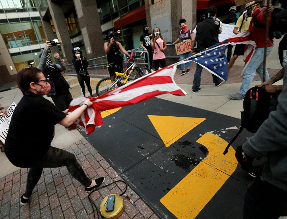 Người biểu tình xé cờ Mỹ ở North Carolina. Ảnh: Reuters