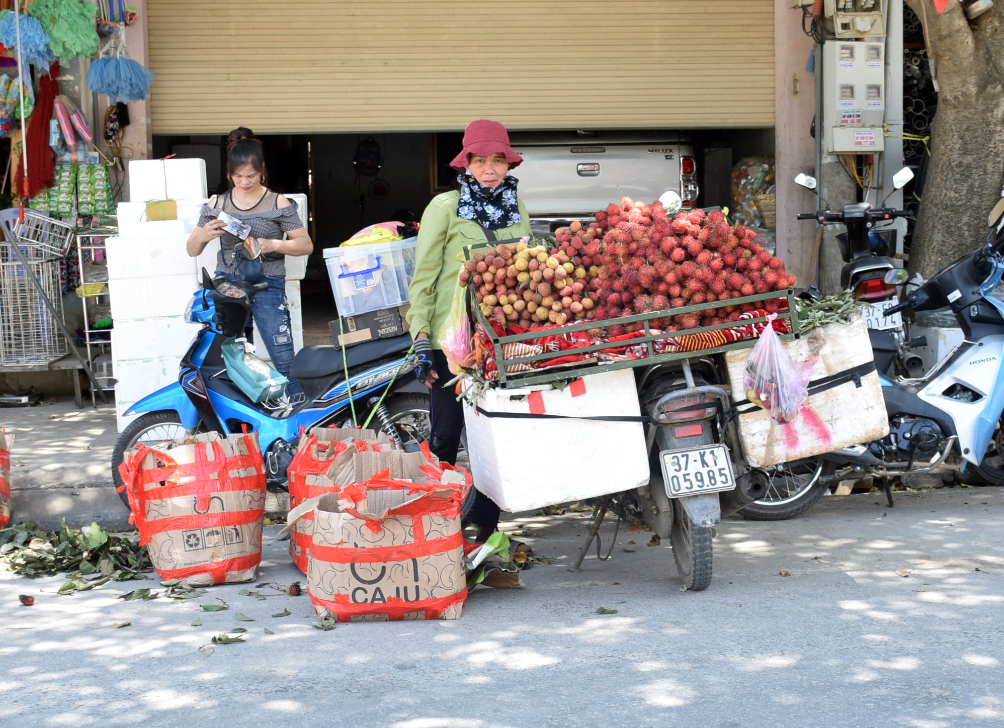 Người phụ nữ này tìm chỗ cos bóng mát của cây xanh trên trục đường chính của thị trấn Mường Xén để bán hoa quả, nhưng giữa trưa nắng không hề có khách hàng. Ảnh: Xuân Hoàng
