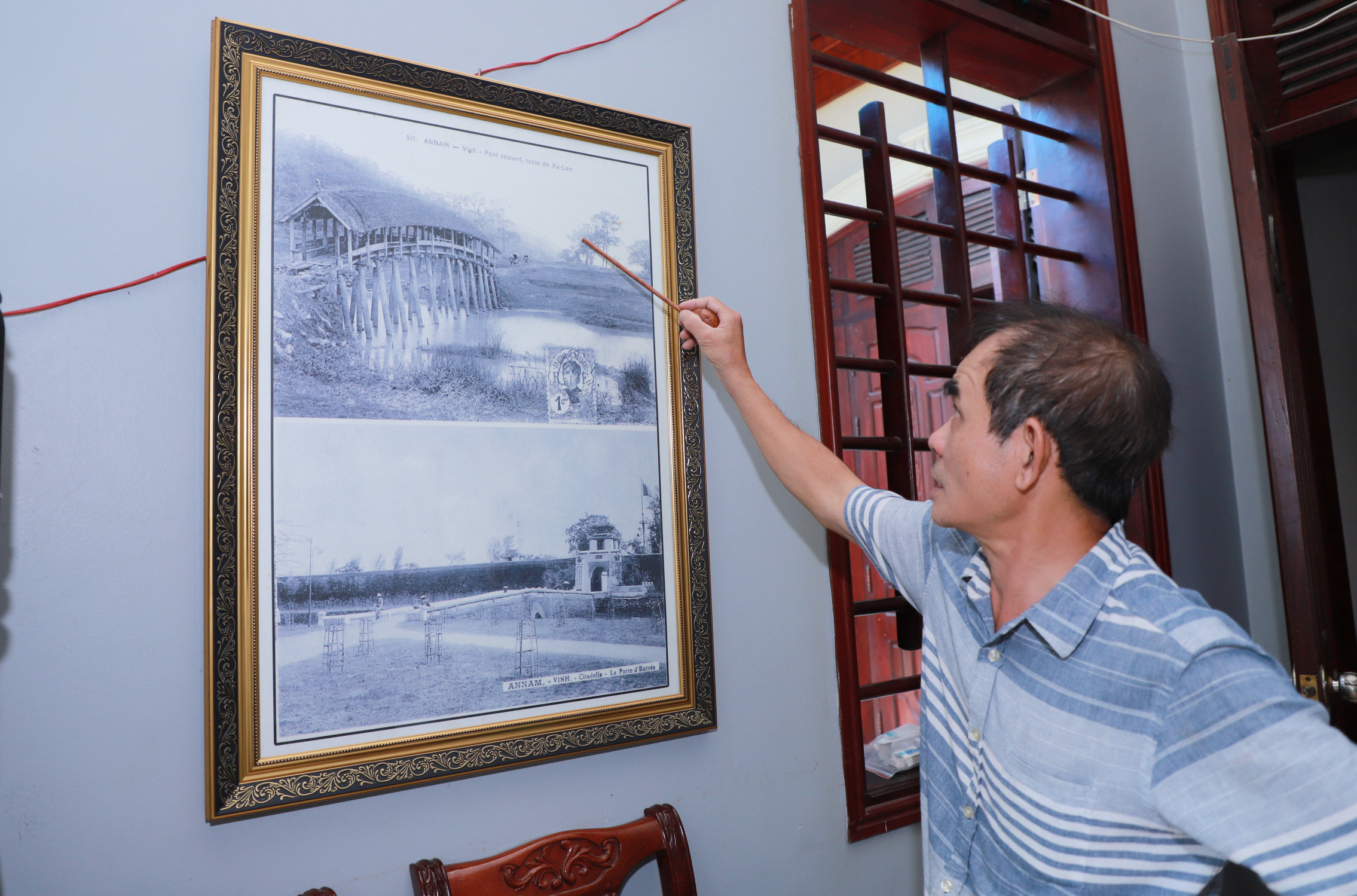 Ông Đinh Văn Tam giới thiệu về bức ảnh cầu ngói Khoa Trường do tổ tiên xây dựng ở quê, tức là xã Nghi Long, Nghi Lộc ngày nay. Ảnh: Thành Duy