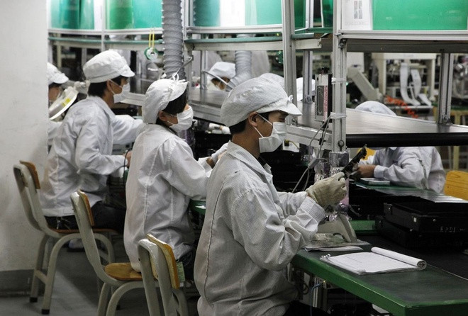 Các công nhân làm việc trên dây chuyền lắp ráp của Foxconn. Ảnh: Bloomberg