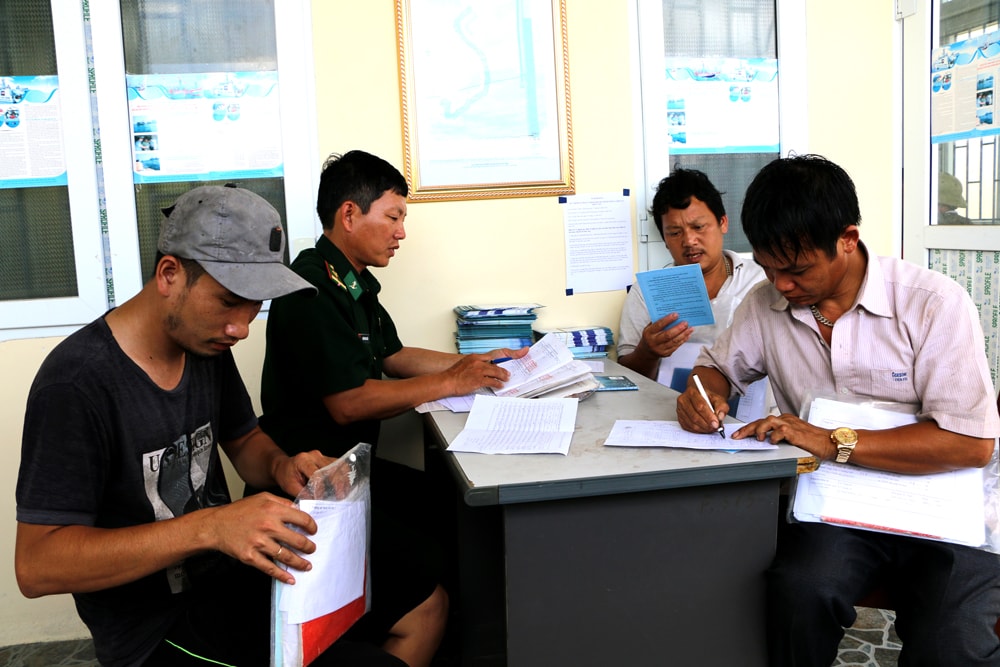 Cán bộ Biên phòng cửa Lạch kiểm tra và làm thủ tục để ngư dân làm thủ tục xuất bến đánh bắt. Ảnh: Nguyễn Hải