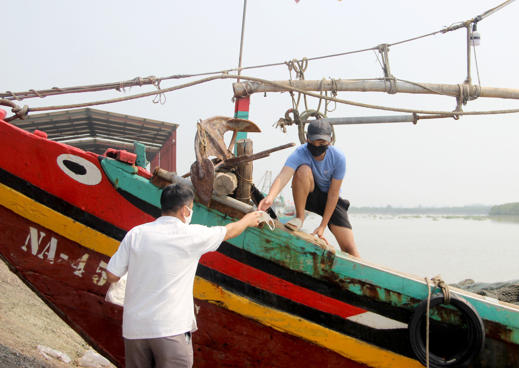 Ngư dân tại cảng Lạch Vạn được phát khẩu trang miễn phí trong lần ra khơi trở lại. Ảnh: Quang An