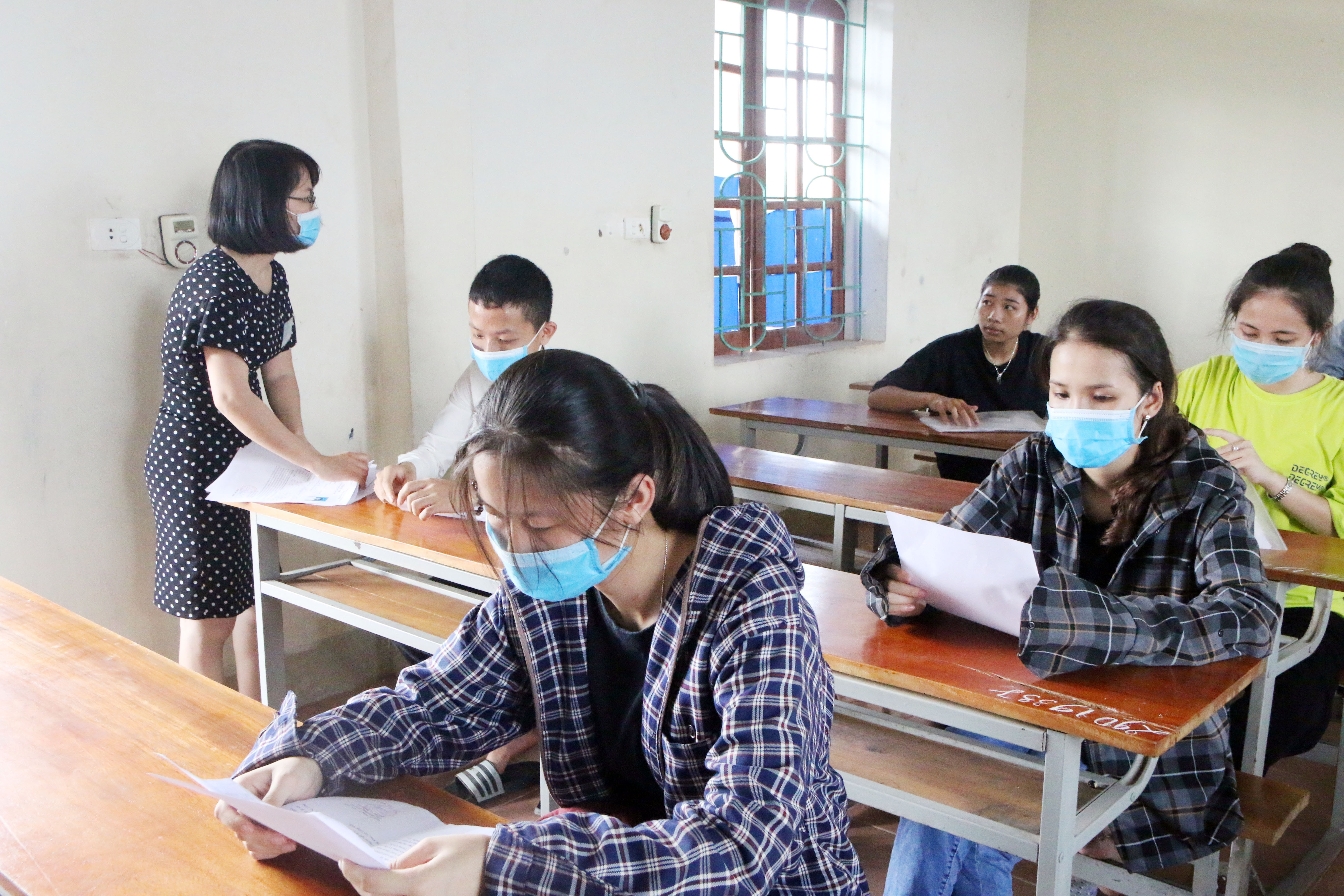 Cán bộ coi thi phổ biến quy chế thi và phát phiếu dự thi cho các thí sinh tại điểm trường THPT Tân Kỳ. Ảnh: Cẩm Tú