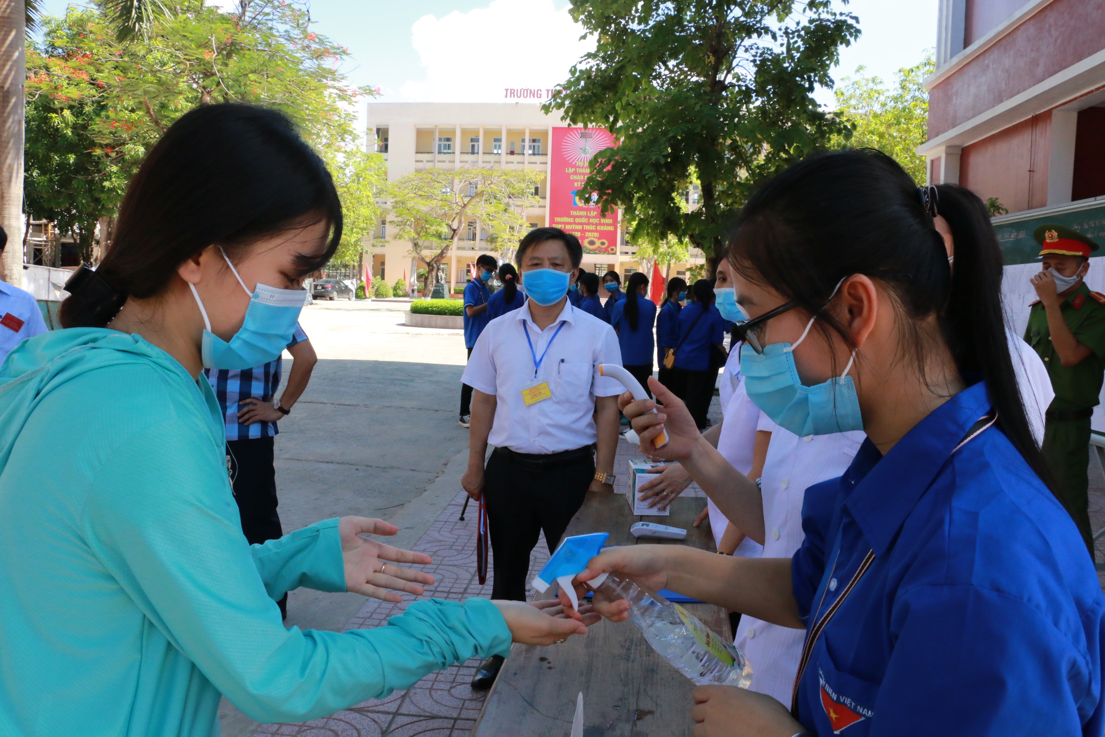 Đội thanh niên tình nguyện hỗ trợ thí sinh rửa tay sát khuẩn trước khi vào phòng thi. Ảnh: Mỹ Hà