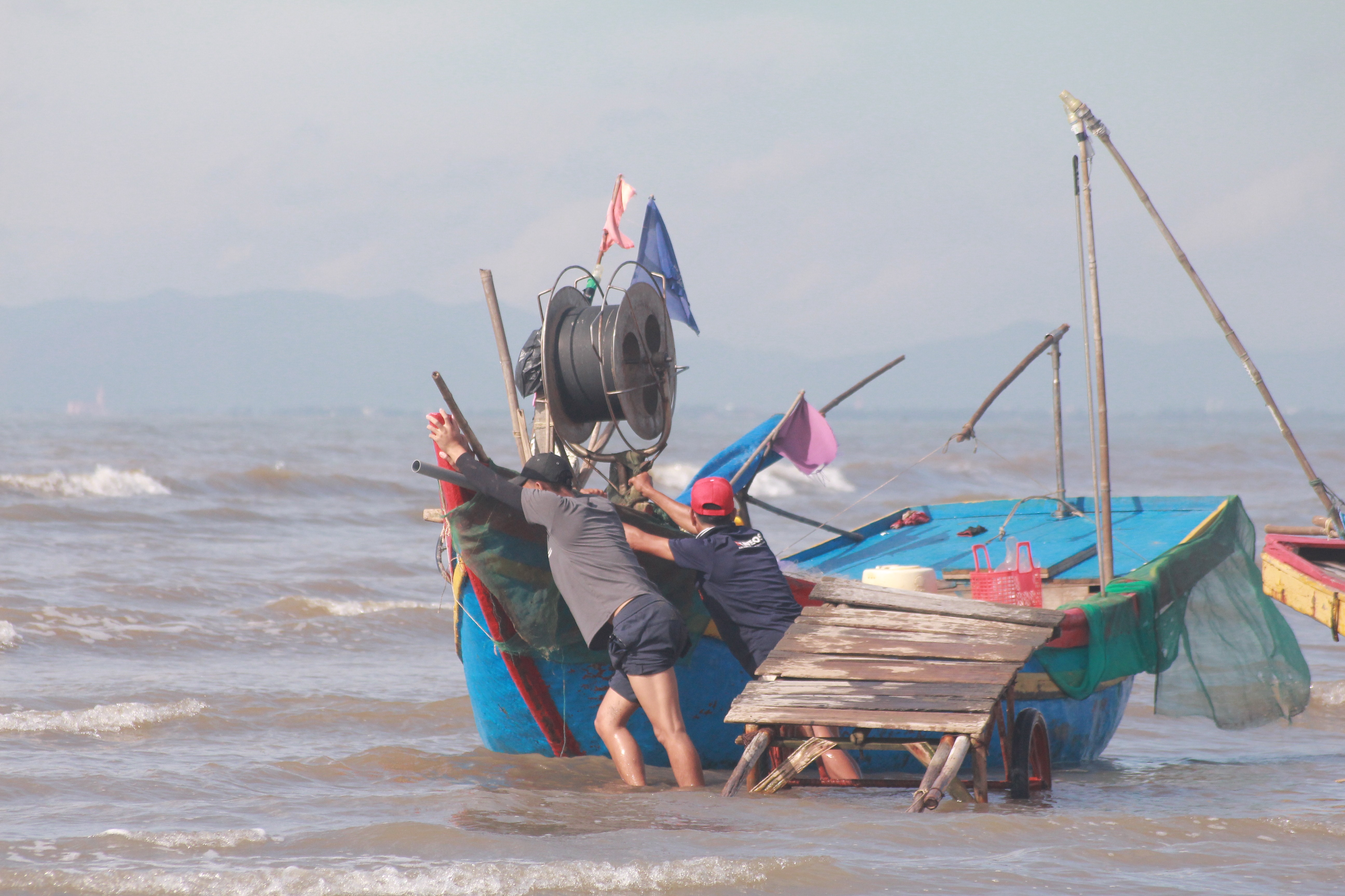 Hôm nay do triều cường xuống nên bà con ngư dân phải đậu thuyền cách bờ cả trăm mét. Ai cũng khẩn trương thả neo, trút từng mẻ lưới mắc đầy hải sản xuống xe để vận chuyển về nhà. Ảnh Việt Hùng