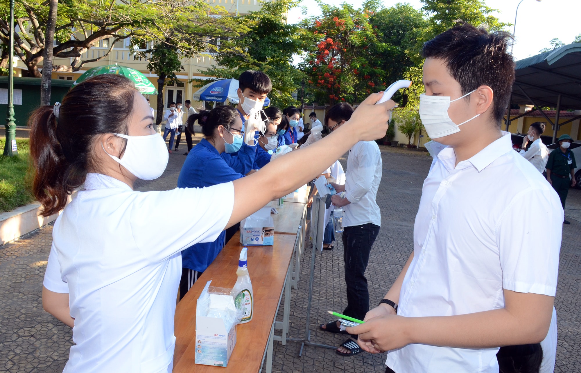 Các thí sinh được đo thân nhiệt, phát khẩu trang mới trước khi bước vào phòng thi. Ảnh: Thành Chung