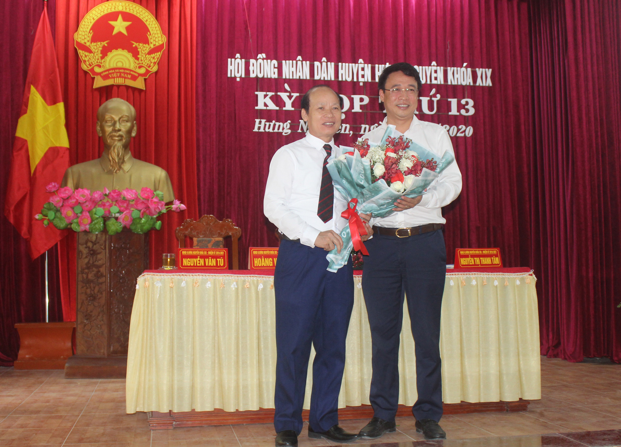 Ông Hoàng Văn Phi, Chủ tịch HĐND huyện tặng  hoa chúc mừng ông Hoàng Anh Tiến
