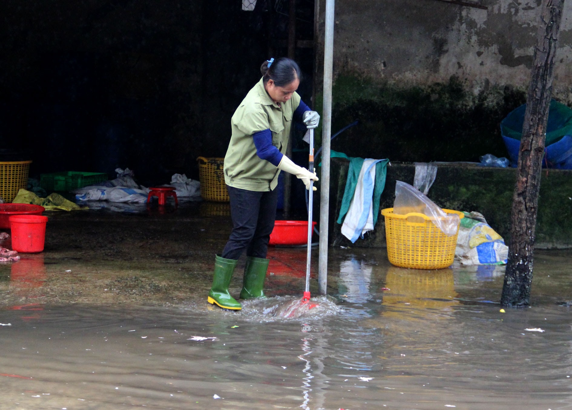 Các tiểu thương liên tục khơi thông các miệng thoát nước để nước rút nhanh hơn. Ảnh: Q.A