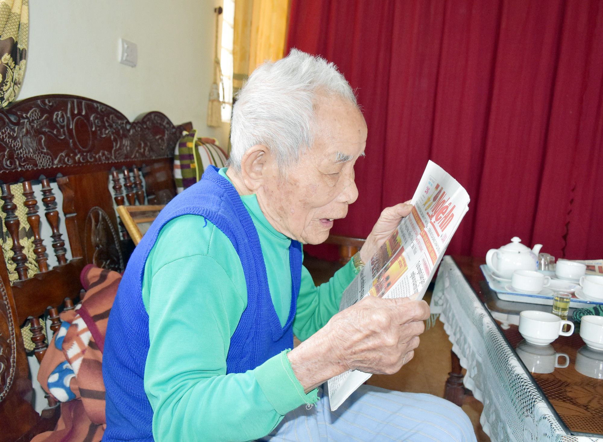 Hàng ngày cụ Hoàng Văn Bàng đọc báo để nắm bắt tin tức. Ảnh: Công Kiên