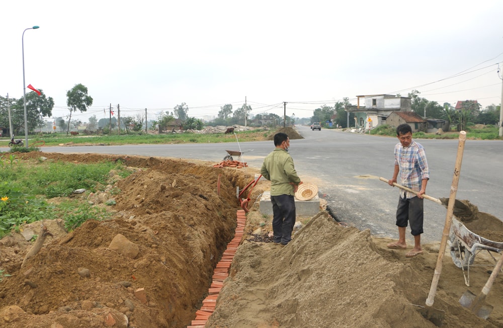 Đơn vị thi công đang lắp đặt kết nối hệ thống chiếu sáng tại ngã tư giữa đường 95 Xuân Đức với đường 35 m qua xã Nghi Đức. Ảnh: Nguyễn Hải