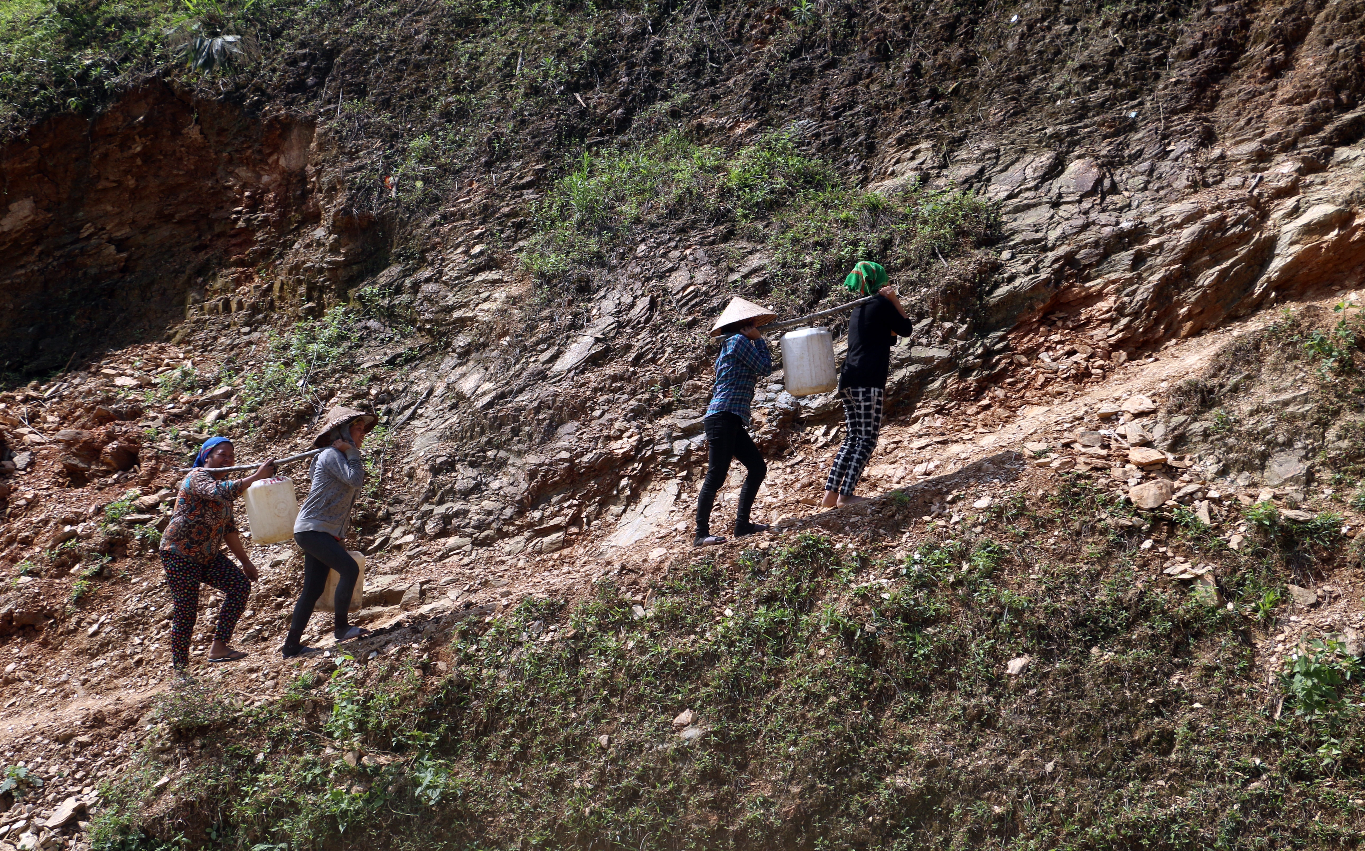 Người dân bản Liên Hương, xã Tam Quang, (Tương Dương) gùi vật liệu xây dựng làm đường nông thôn mới. Ảnh: Hồ Phương