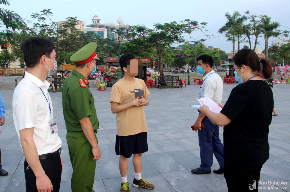 Lực lượng chức năng phường Trường Thi lập biên bản xử lý trường hợp không đeo khẩu trang tại Quảng trường Hồ Chí Minh chiều 6/5. Ảnh: Quang An