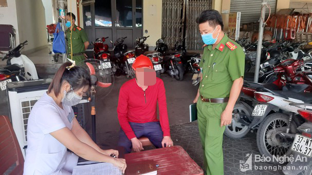 Lực lượng chức năng lập biên bản xử phạt người đi chợ không đeo khẩu trang. Ảnh: Hồng Quang