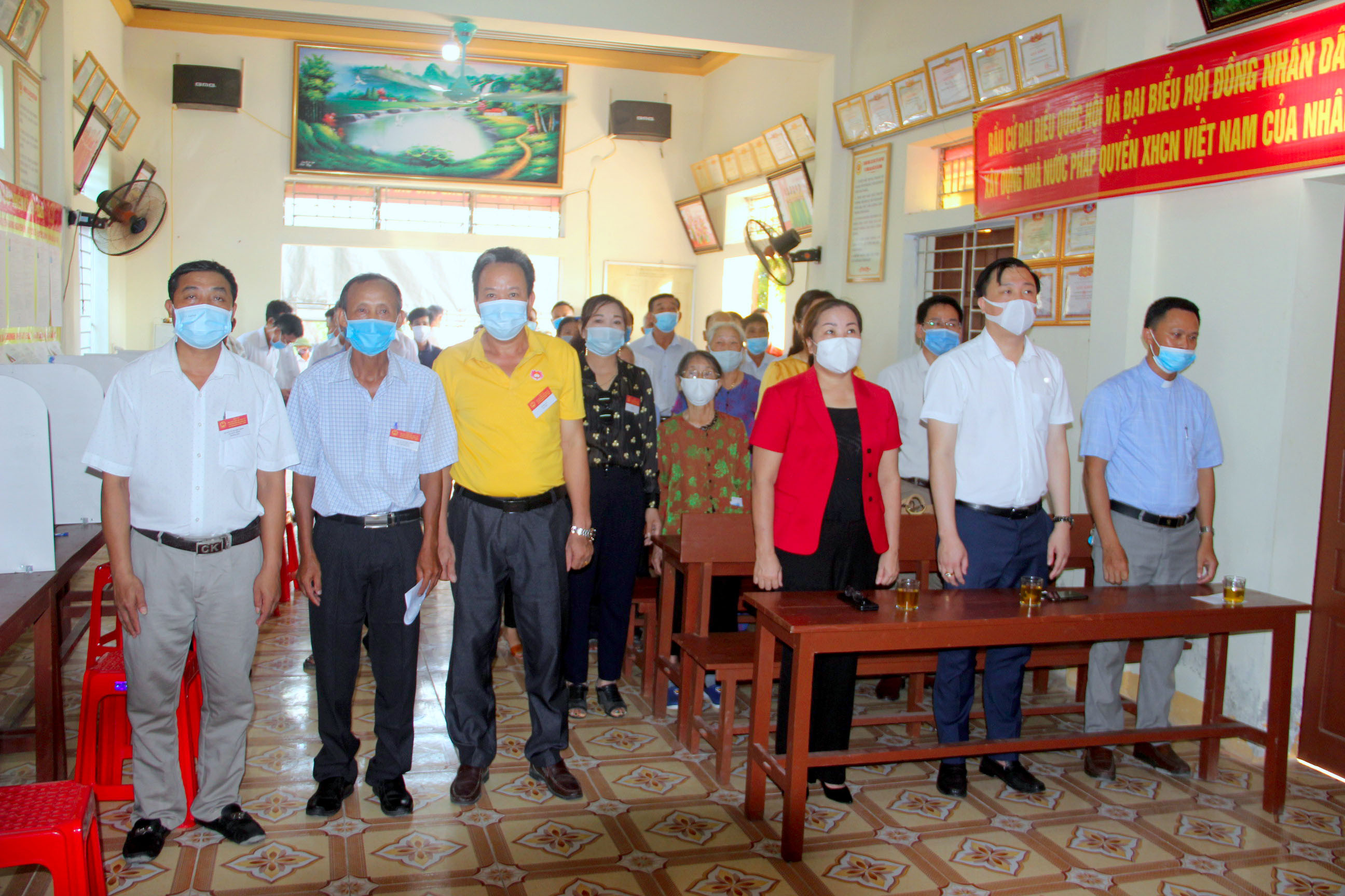 Các đại biểu và cử tri tại khu vực bỏ phiếu số 5 xã Hưng Thịnh, Hưng Nguyên nghiêm trang thực hiện nghi lễ chào cờ. Ảnh: Quang An