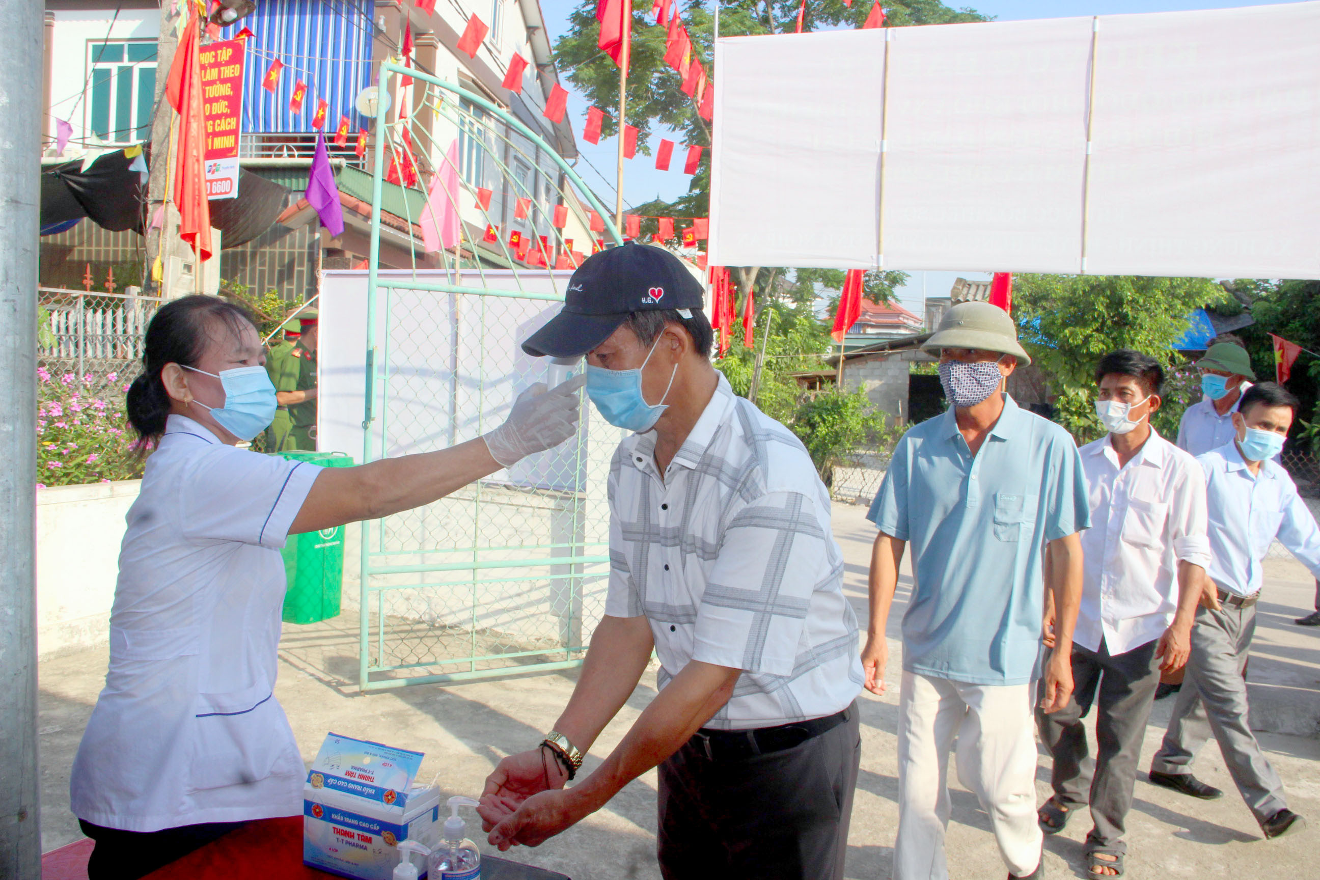 Cử tri tại xã Hưng Thịnh, Hưng Nguyên được kiểm tra y tế đầy đủ trước khi vào bỏ phiếu. Ảnh: Quang An
