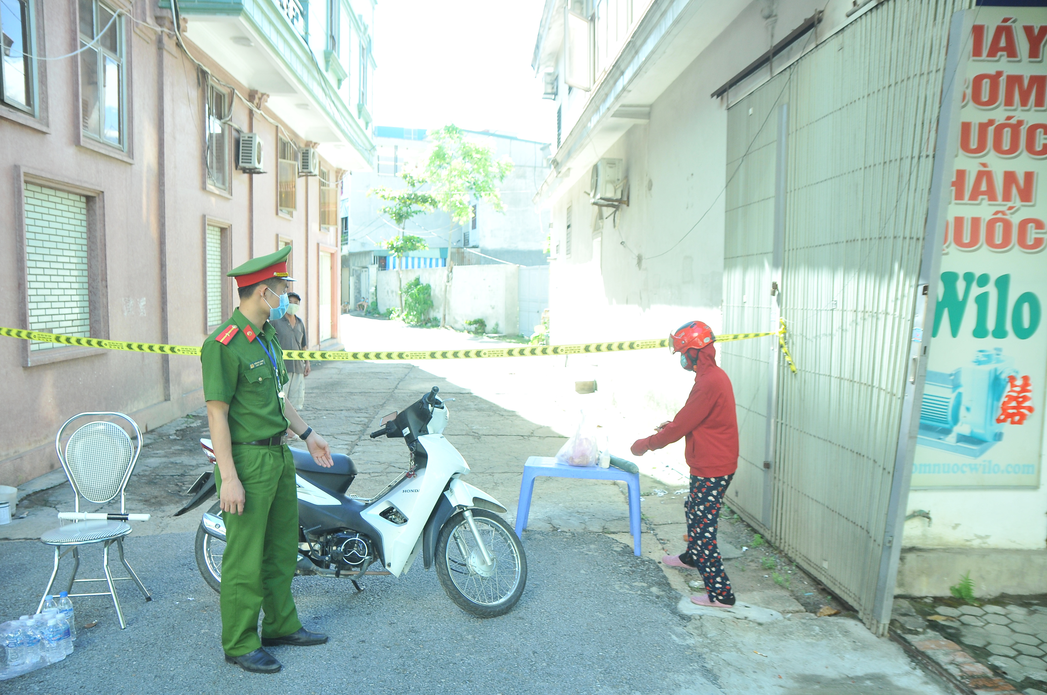 Hướng dẫn người dân để đồ tiếp tế lên bàn sau đó người nhà mới đến lấy. Ảnh: Tiến Đông