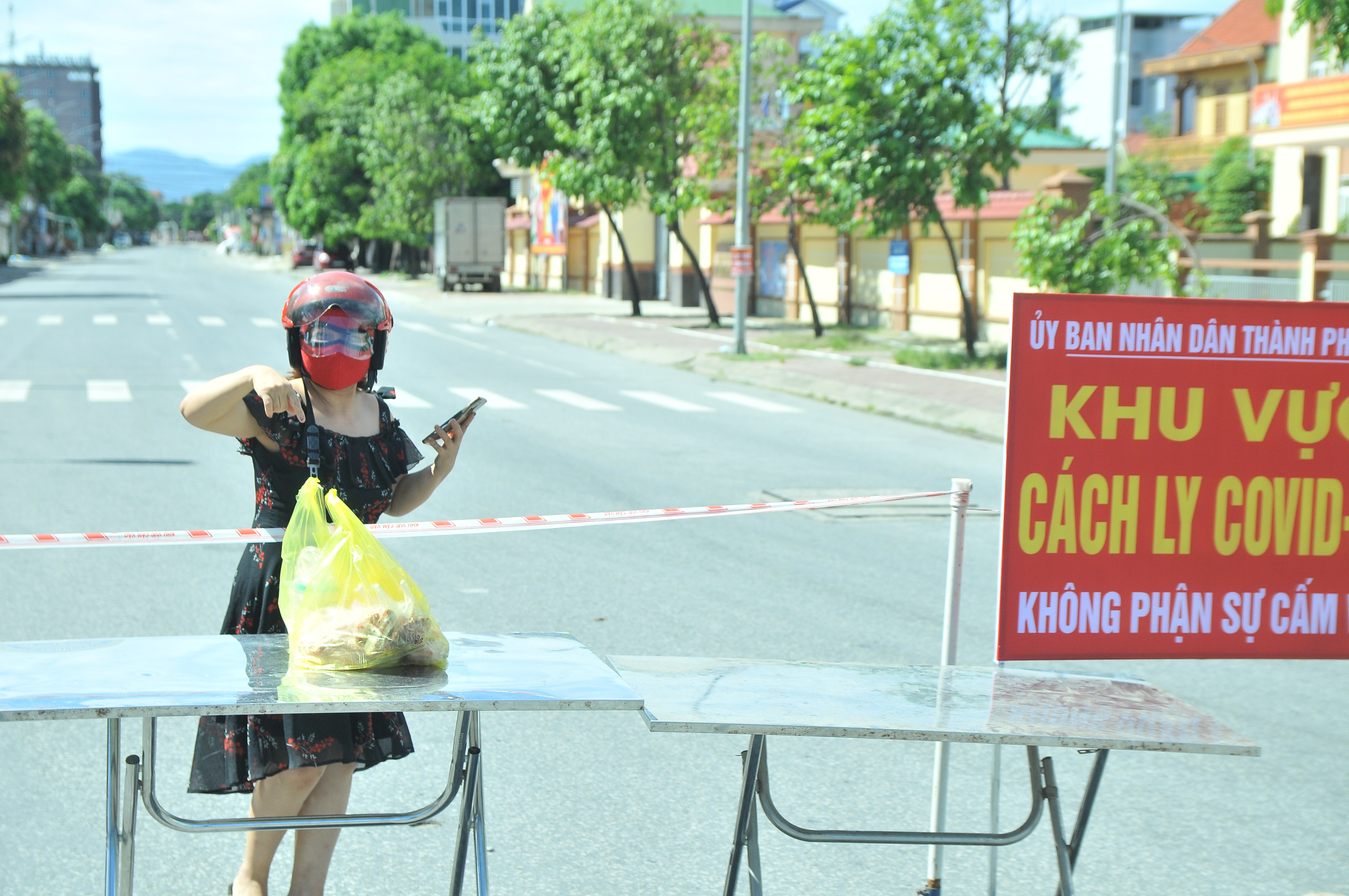 Người dân nhận thực phẩm tại điểm chốt canh gác đầu đường Nguyễn Duy Trinh, phường Hưng Dũng. Ảnh: Tiến Đông