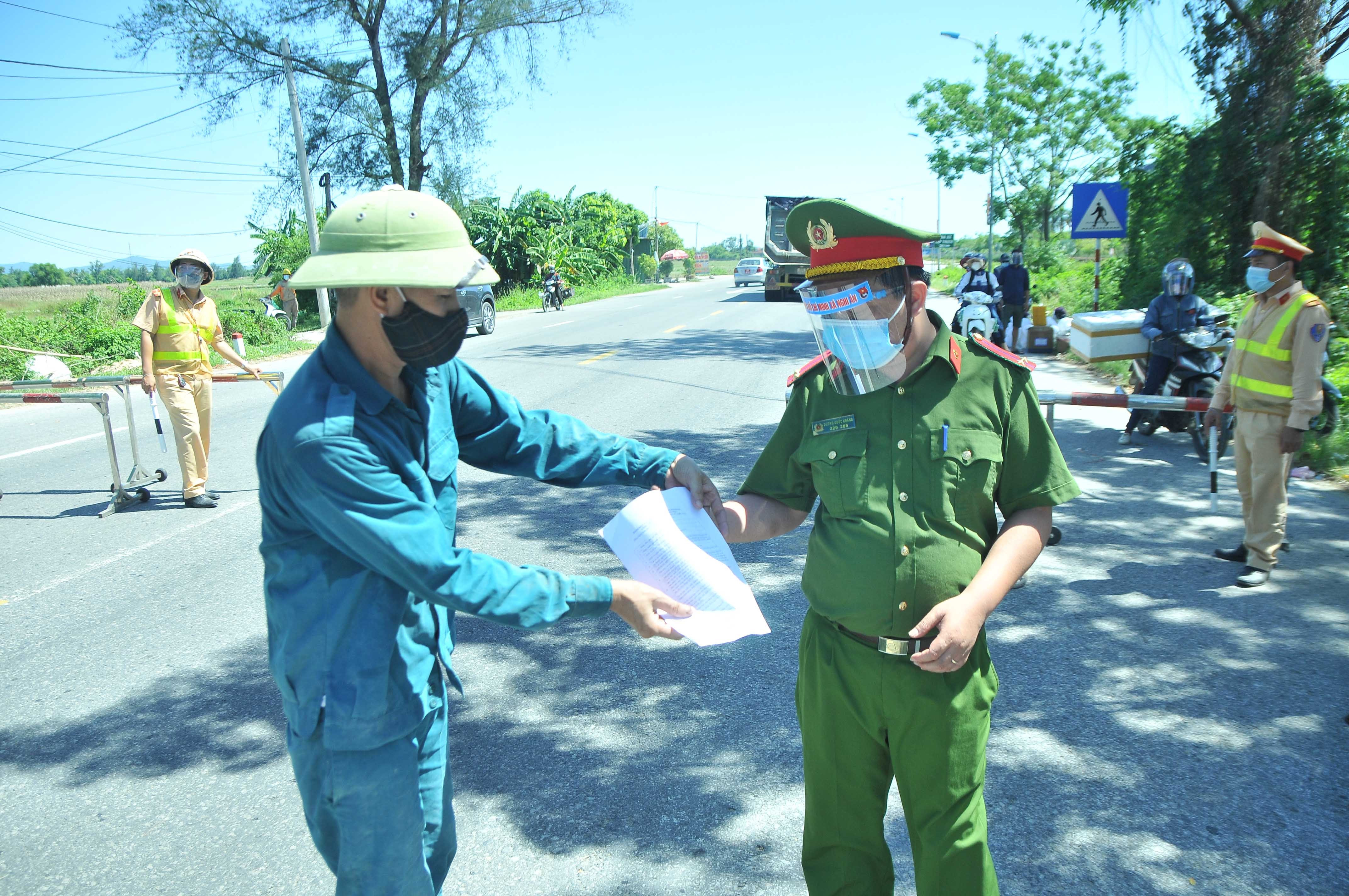 Một lái xe chở vật liệu xây dựng xuất trình giấy tờ tại điểm chốt trên Quốc lộ 46 tại xã Nghi Ân