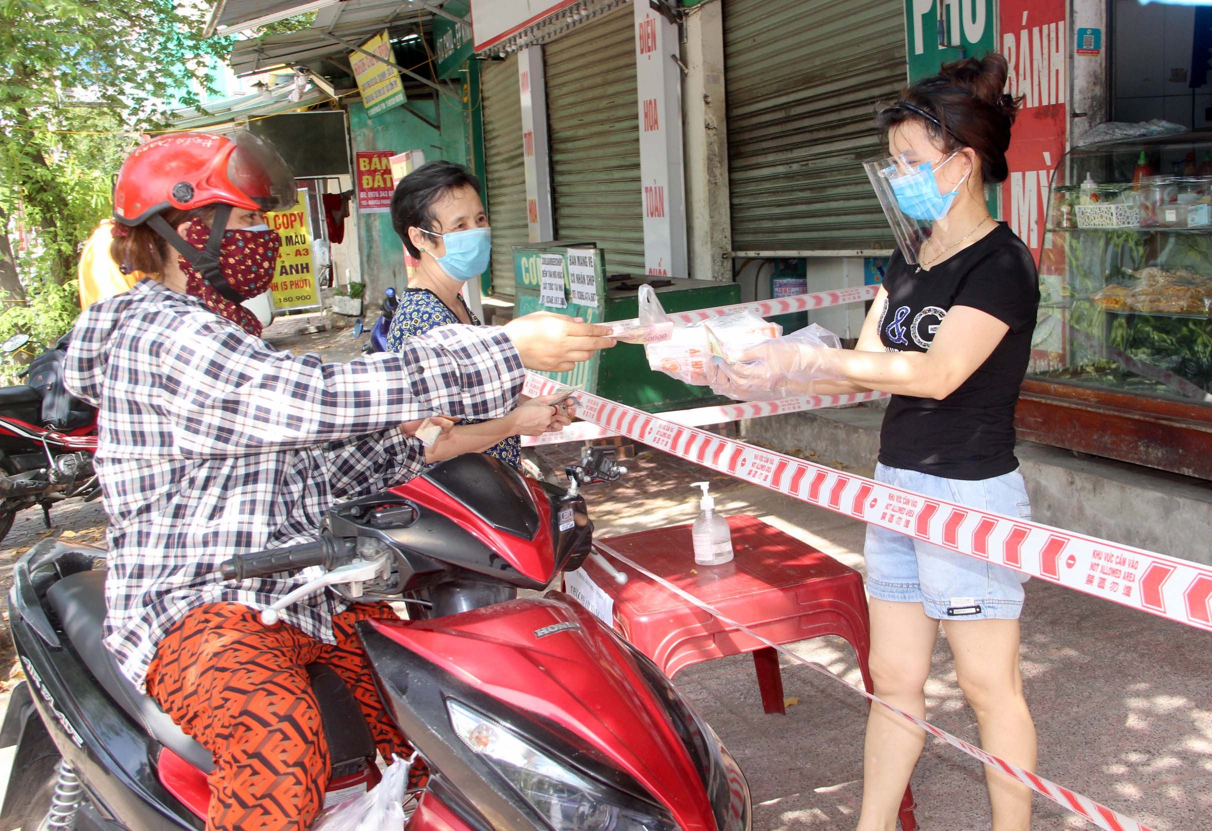 Việc bán hàng kiểu mới này tuy gặp nhiều khó khăn nhưng đảm bảo về an toàn phòng dịch nên được người dân đồng tình. Ảnh: Nguyên Châu