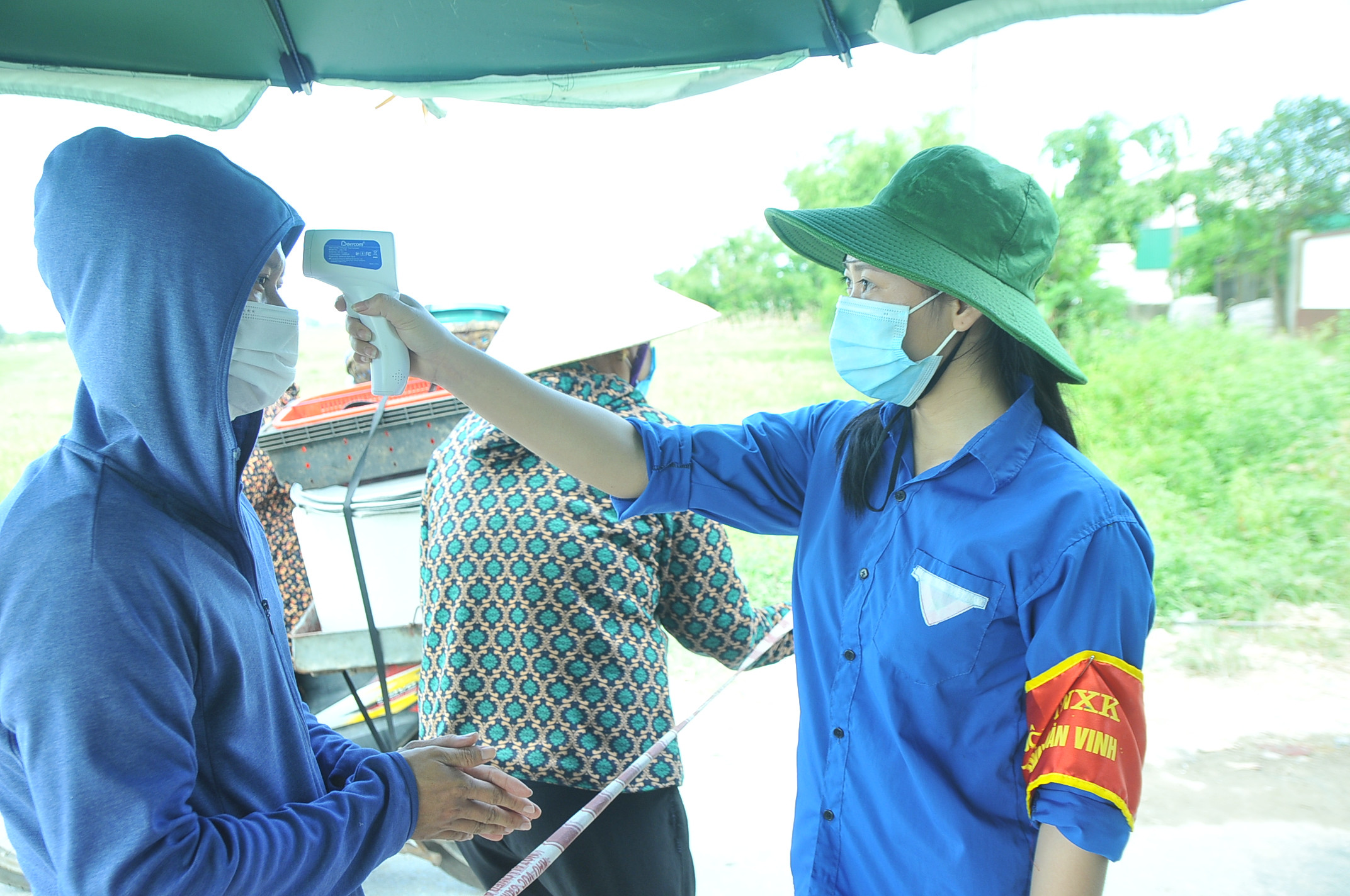 Nguyễn Thị Hương Trà - Sinh viên năm thứ 4 Đại học Vinh đang làm nhiệm vụ kiểm tra thân nhiệt cho người dân tại chốt kiểm soát. Ảnh: Tiến Đông