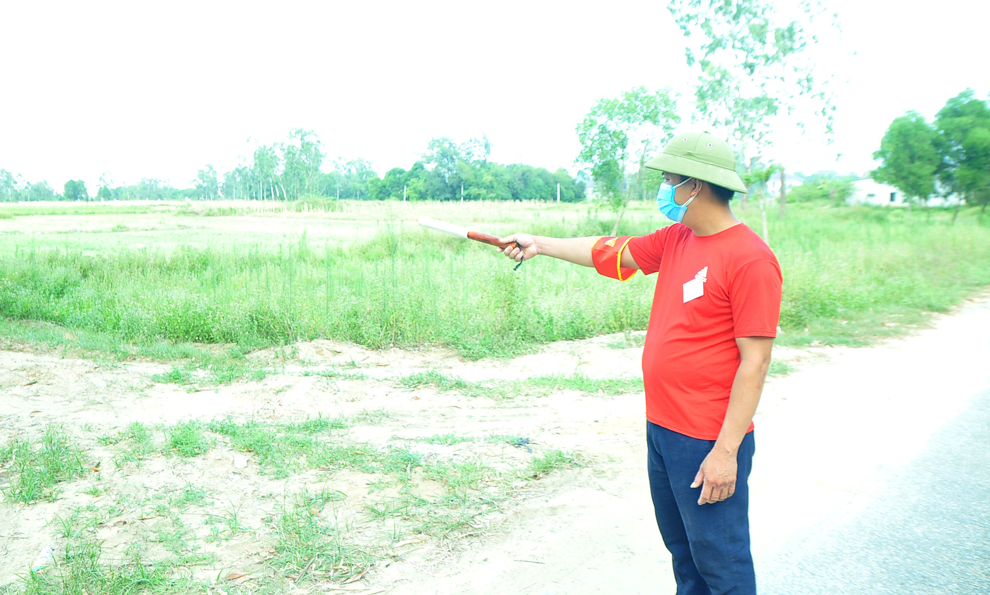 Nguyễn Anh Đức đứng chốt một mình trước cánh đồng, nơi có con đường đất nối Nghi Ân với xã Nghi Phong (Nghi Lộc). Ảnh: Tiến Đông