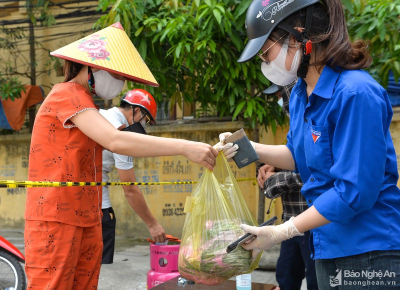 Các Shipper áo xanh hỗ trợ người dân trong khu vực bị phong tỏa ở phường Hà Huy Tập (TP.Vinh). Ảnh: Thành Cường