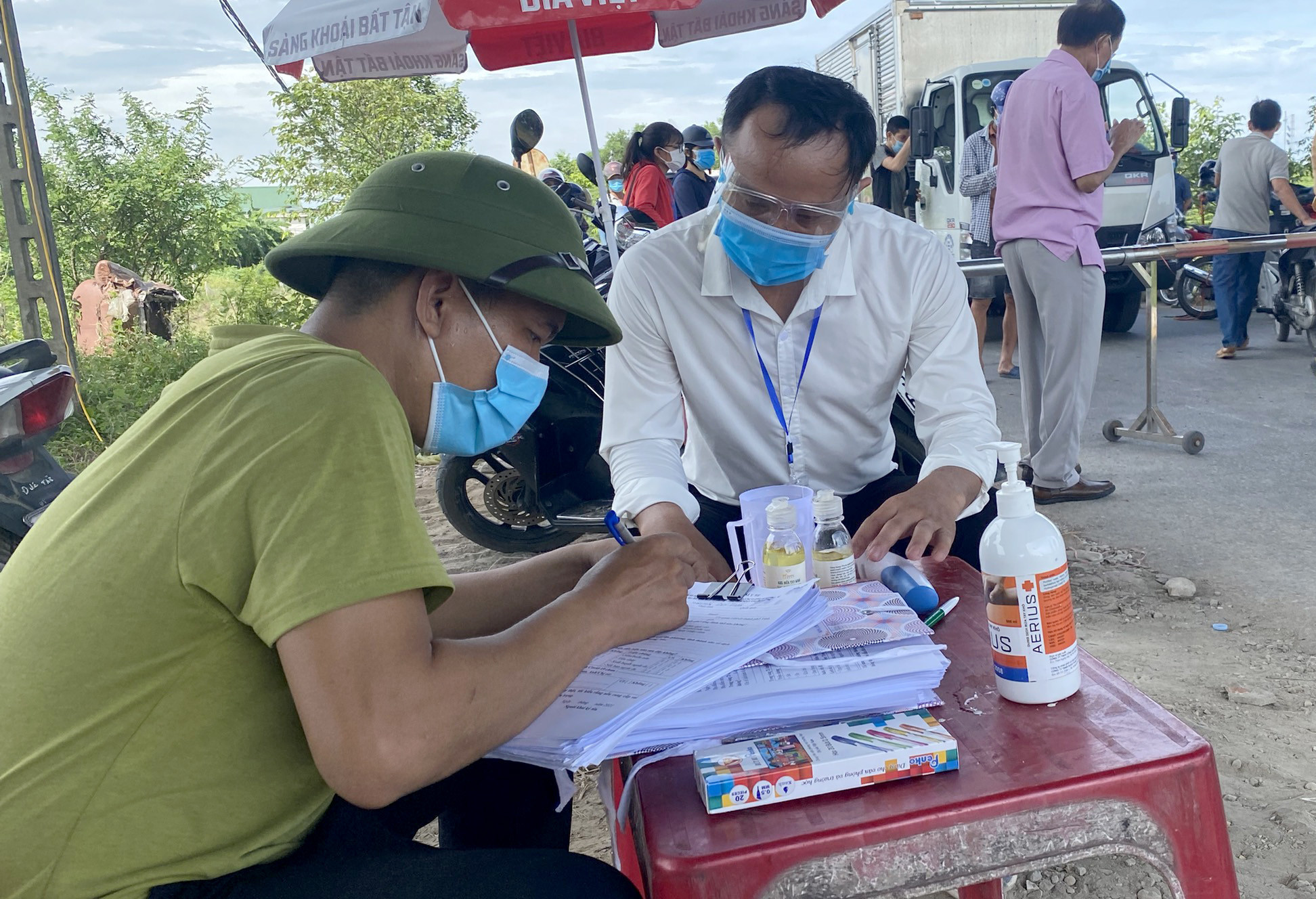 Thầy Đinh Việt Đức (áo trắng), hướng dẫn người dân làm tờ khai y tế tại chốt số 5 trên đường Trần Đình San thuộc phường Vinh Tân. Ảnh: Tiến Đông