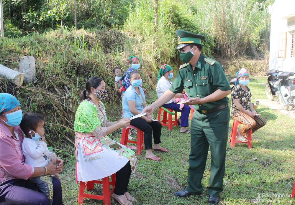 Cán bộ Biên phòng phát tờ rơi tuyên truyền phòng chống dịch Covid-19 cho người dân. Ảnh: Mai Hoa