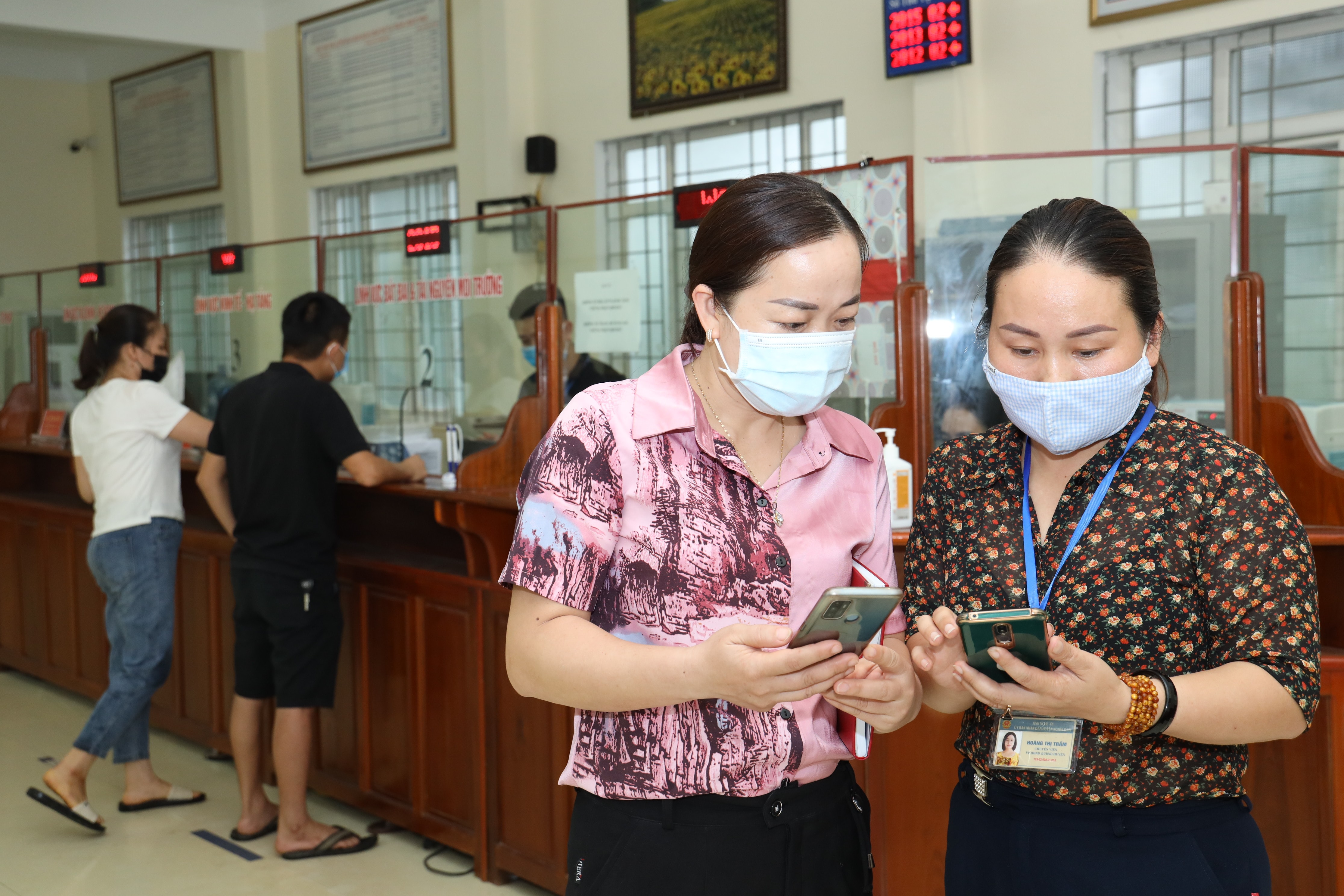 Cán bộ Trung tâm một cửa huyện Nghĩa Đàn hướng dẫn người dân tra cứu thủ tục hành chính trên địa thoại di động. Ảnh Nguyên Nguyên