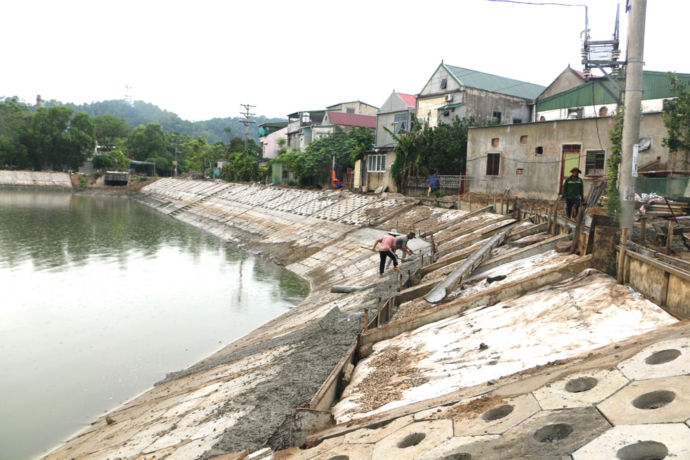 Công nhân thi công mái kè hồ điều hòa Trạm bơm số 3 phường Bến Thủy, TP Vinh. Trạm bơm này có công suất 20.000 m3 nên sau khi cải tạo đạt 1,1 ha và mở rộng cống thì công suất bơm thoát đạt tối đa. Ảnh: Nguyễn Hải