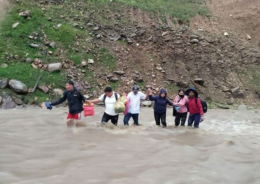 Để an toàn hơn, nhiều giáo viên phải dàn hàng ngang để dìu nhau qua đoạn nước chảy xiết. Ảnh: Đào Thọ