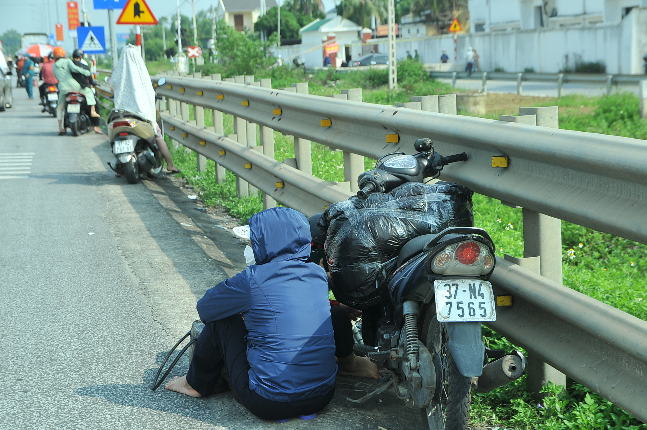 Khi đến chốt kiểm soát, do không có giấy tờ đầy đủ nên nhiều người dân đành phải ngồi vạ vật bên vệ đường chờ người nhà mang giấy tờ đến. Ảnh: Quang An