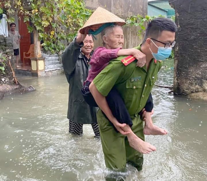 Lực lượng công an hỗ trợ người già ra khỏi vùng ngập lụt. Ảnh: Việt Hùng