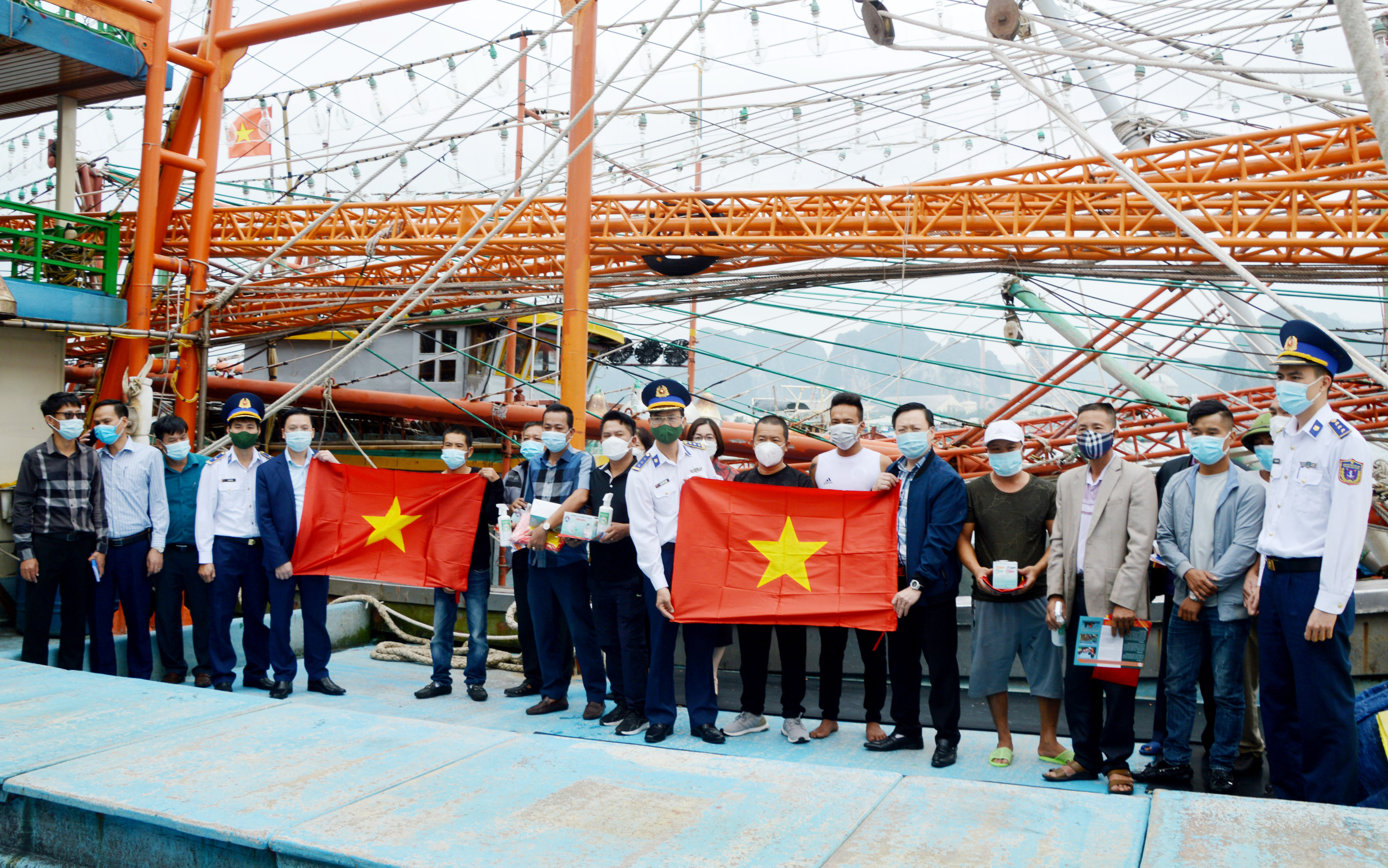 Tặng cờ Tổ quốc, sổ tay tuyên truyền, khẩu trang, nước sát khuẩn cho bà con ngư dân Quảng Ninh. Ảnh: Mạnh Thường