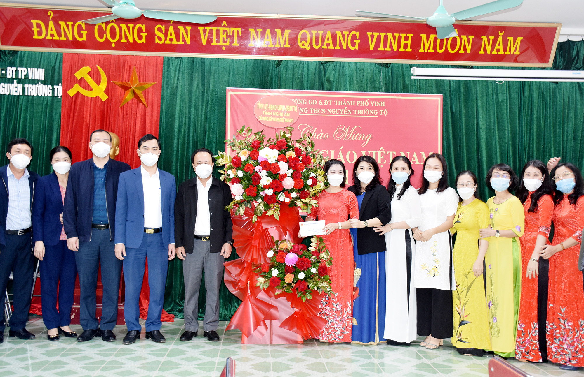 Đồng chí Nguyễn Nam Đình và các thành viên Đoàn công tác của tỉnh tặng hoa cho tập thể giáo viên Trường Ảnh: Công Kiên