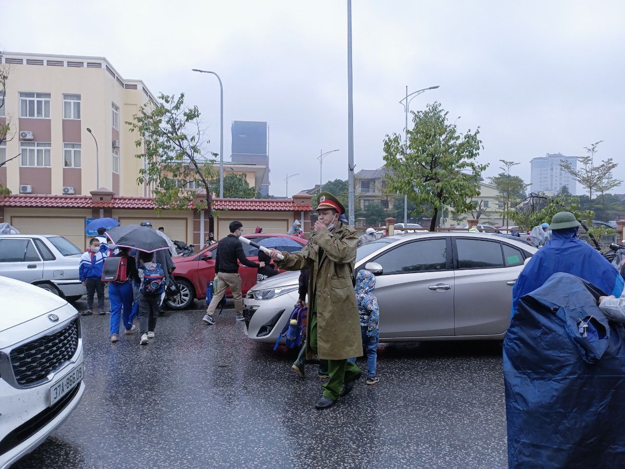 Lực lượng chức năng đã phải dầm mưa để phân luồng giao thông trước cổng trường vào giờ tan học. Ảnh: Tiến Đông 