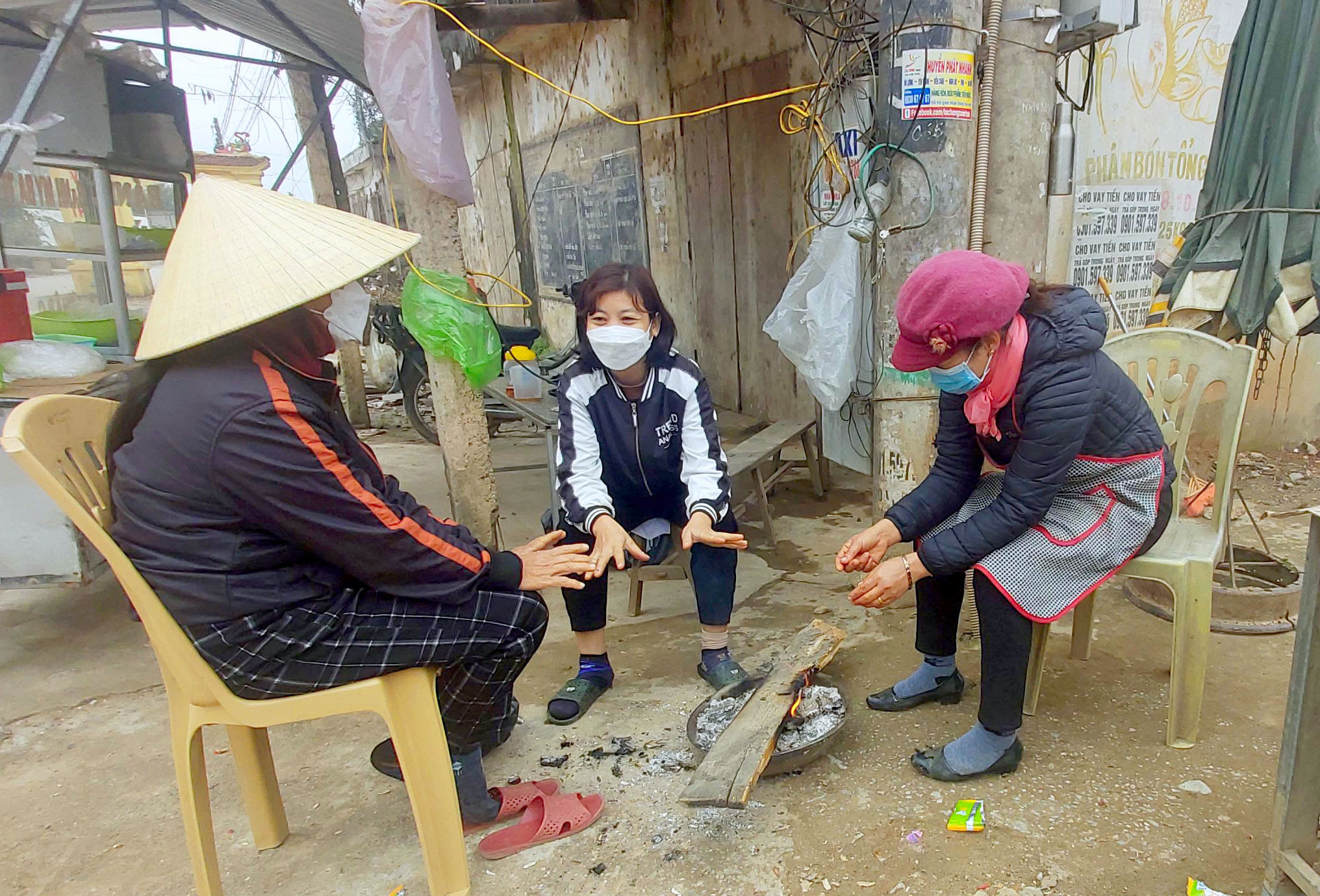 Nhiều tiểu thương tại chợ Thị trấn Yên Thành tranh thủ sưởi ấm lúc vắng khách. Ảnh: Xuân Hoàng
