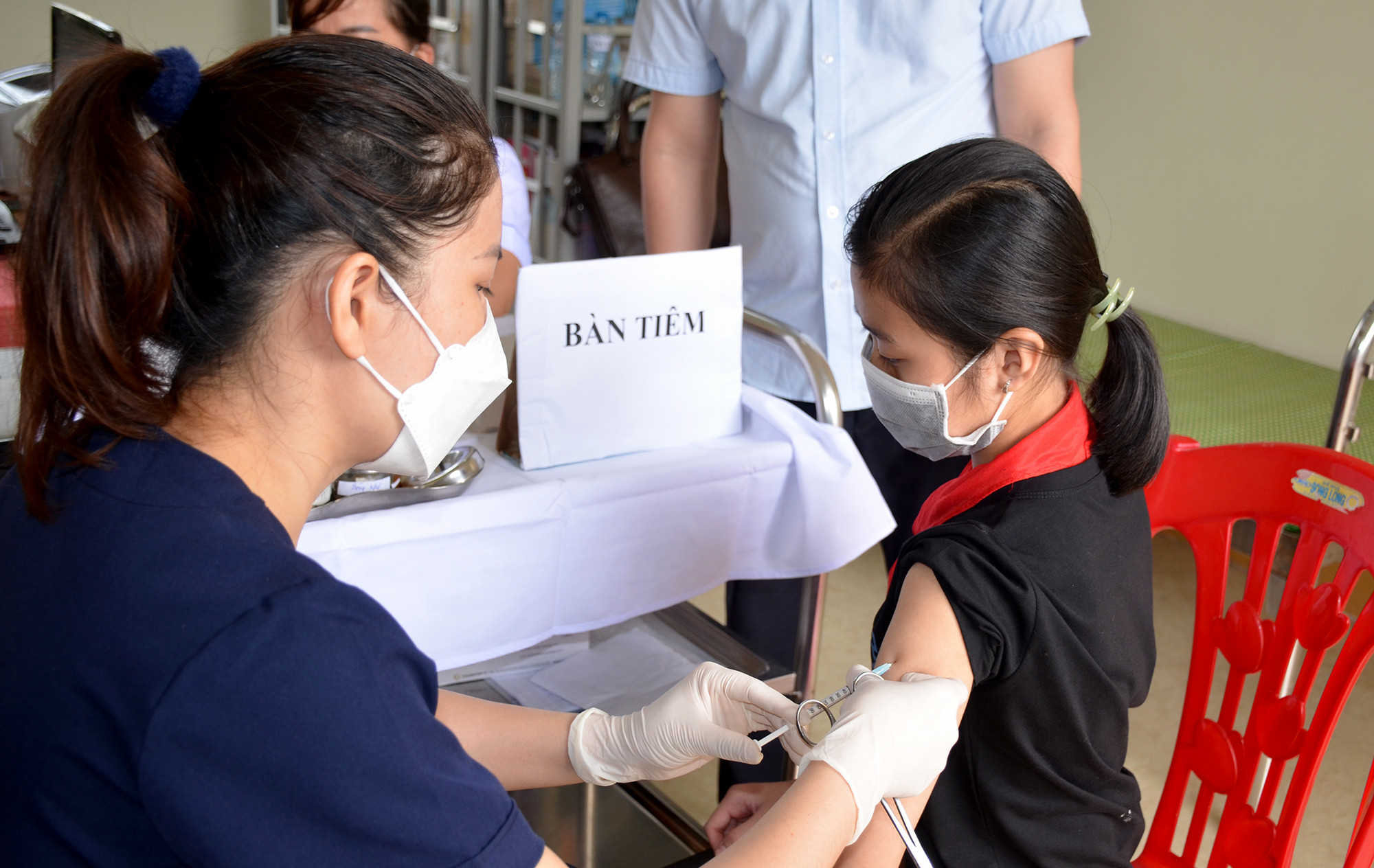 Cháu Phạm Hồng Thơm (11 tuổi) là người đầu tiên được tiêm vắc xin phòng Covid-19 tại điểm tiêm  Trường Trung học Cơ sở Lam Thành. Ảnh: Mỹ Hà