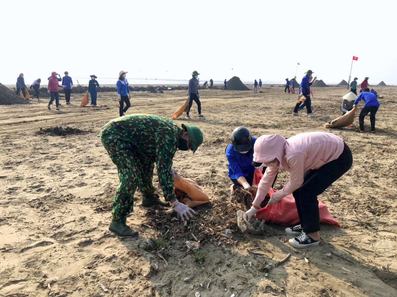 Các chiễn sỹ Đồn Biên phòng Diễn Thành chung tay cùng người dân thu dọn rác tại bãi biển Diễn Thành. Ảnh: Q.A