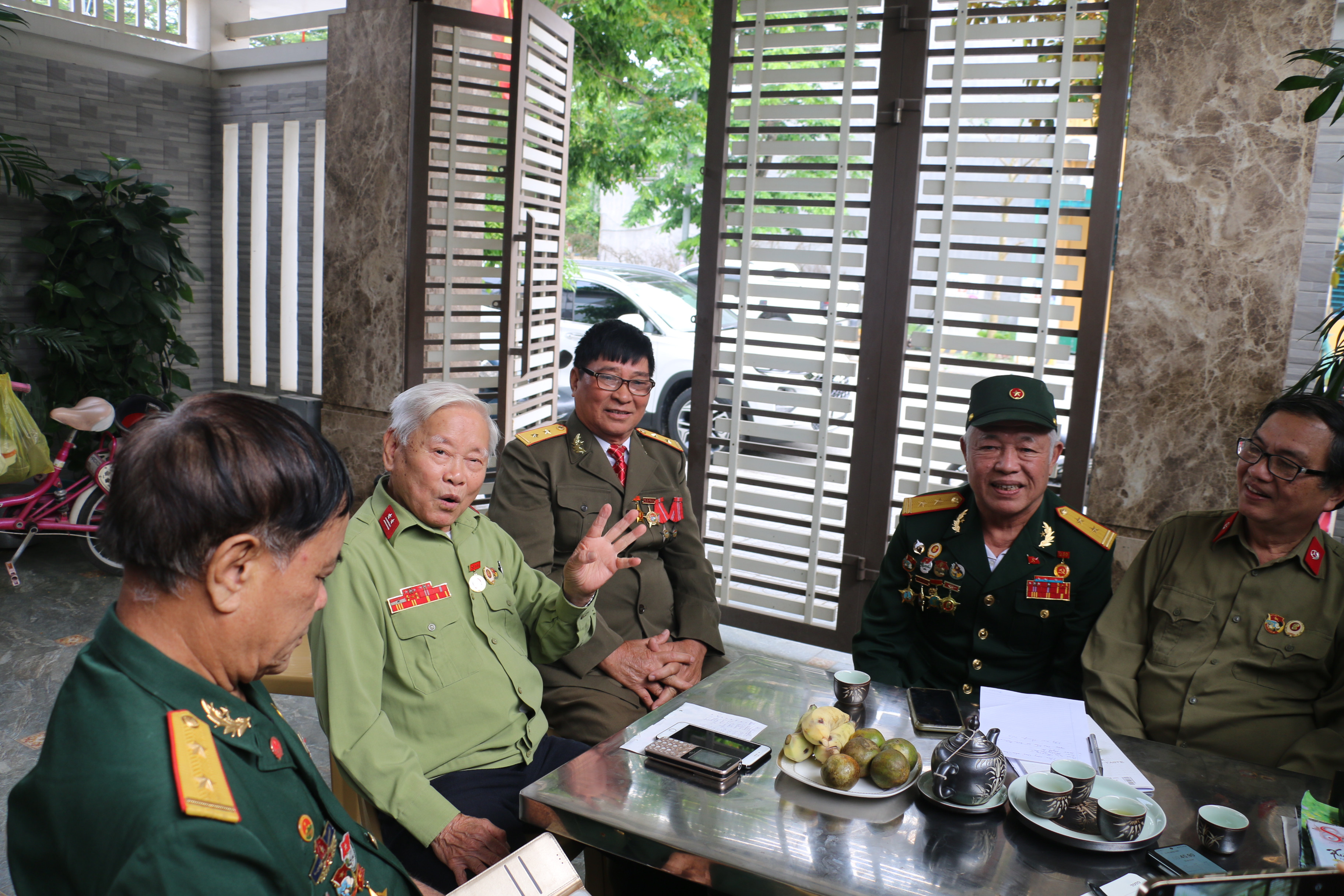 Cựu chiến binh Trần Xuân Kình đang xem lại tài liệu cùng với các đồng đội cũ. Ảnh: MH