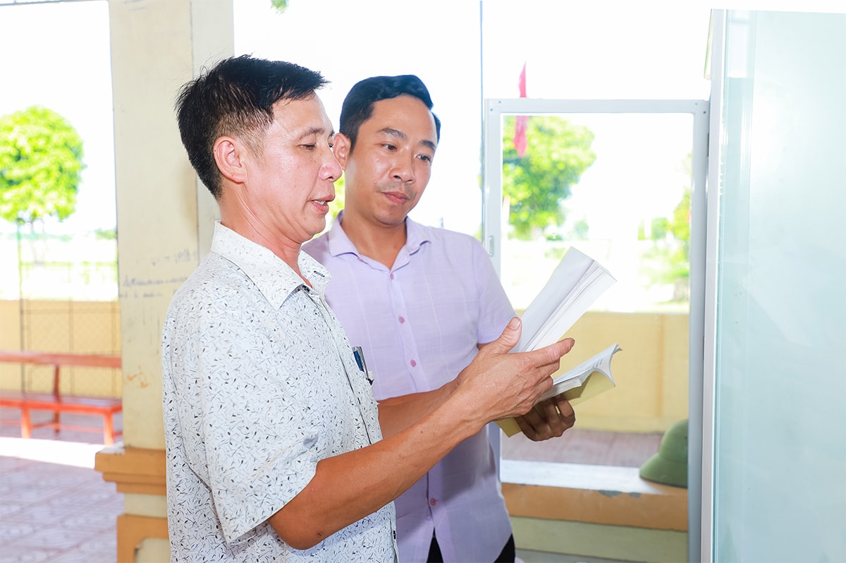 Ông Trần Ngọc Cảnh (trái ảnh) sắp xếp, bố trí tủ sách tại Nhà văn hóa xóm.