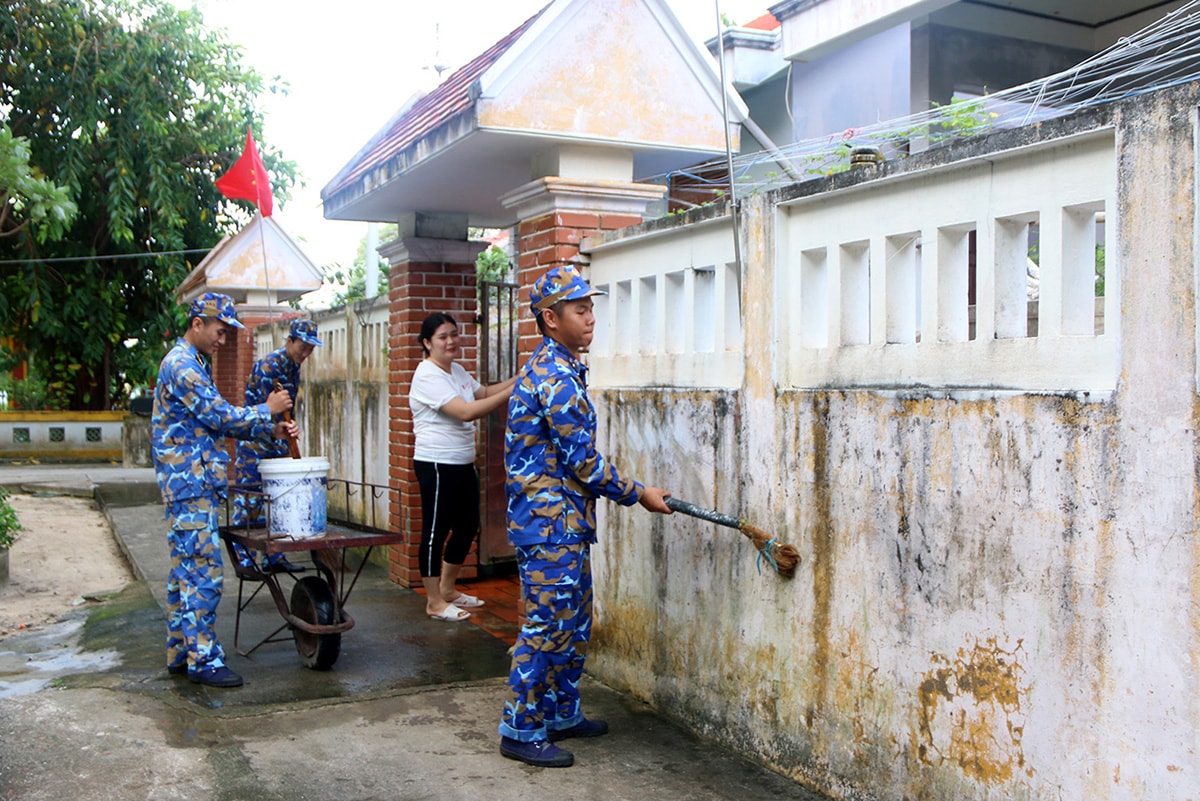 Các chiến sĩ phân đội 2, đảo Sinh Tồn xuống giúp người dân quét vôi lại hàng rào để chuẩn bị đón Tết.