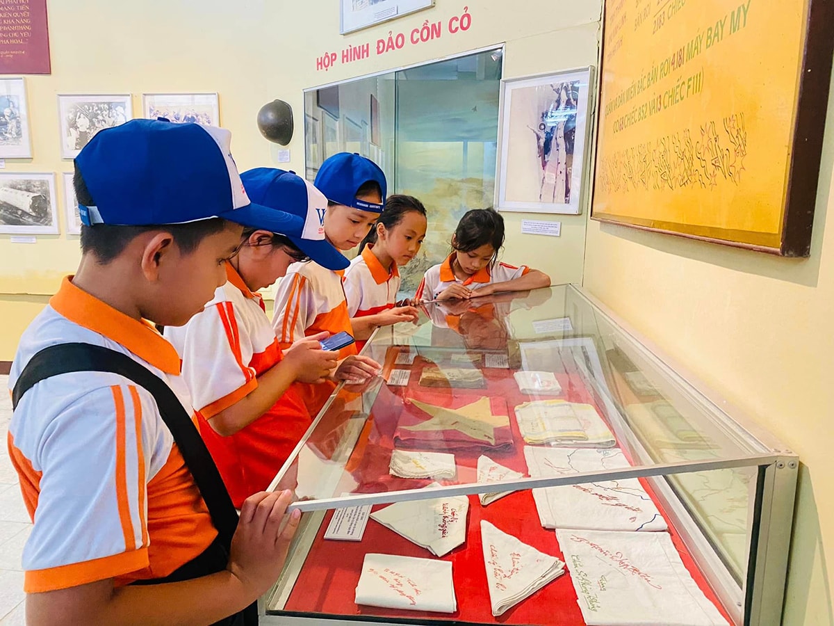 Các học sinh đang tìm hiểu những lá cờ được lưu giữ ở Bảo tàng Quân khu IV.